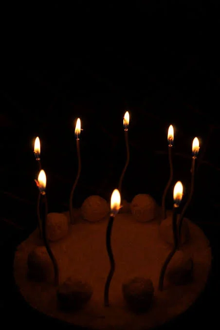 Birthday Sad Shayari showing a lonely birthday cake and candles in a dim room