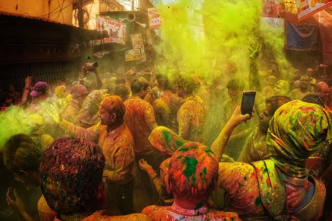 Holi Sad Shayari In Hindi showing a Holi street celebration with music, colors, and a lively crowd