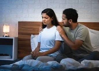 Husband Wife Sad Shayari showing a sad wife sitting beside her husband while looking away