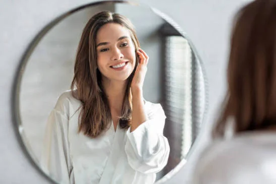 Self Love Shayari In English showing a happy woman smiling at her reflection in a round mirror